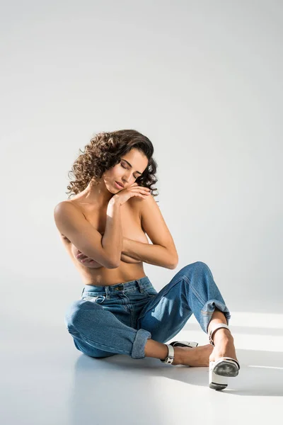 Elegante chica en topless en jeans posando con los ojos cerrados sobre fondo gris - foto de stock