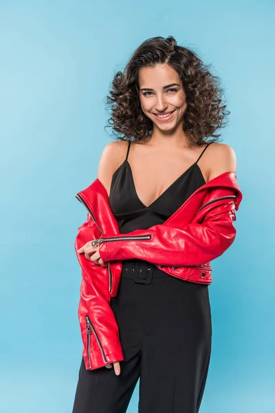 Encantadora joven en chaqueta roja de pie sobre fondo azul - foto de stock