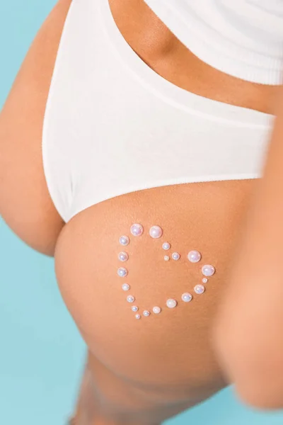 Cropped view of woman in white panties with heart sign on blue background — Stock Photo