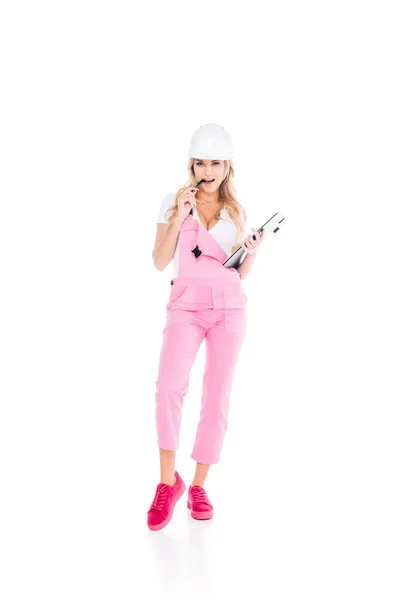Handy woman in pink overalls, hardhat with paper clipboard pen on white background — Stock Photo