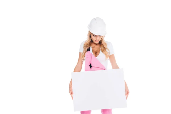 Blonde femme pratique en uniforme rose, casque de sécurité tenant la plaque isolée sur blanc — Photo de stock