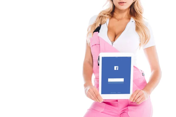 Vista recortada de la mujer práctica en uniforme rosa celebración tableta digital con aplicación de facebook en la pantalla aislada en blanco - foto de stock