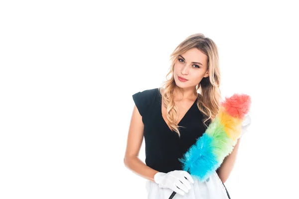 Attractive blonde housemaid in black uniform, apron with multicolored duster isolated on white — Stock Photo
