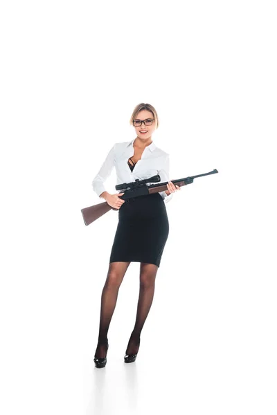 Profesora rubia en blous con escote abierto, gafas y falda sosteniendo rifle sobre fondo blanco - foto de stock