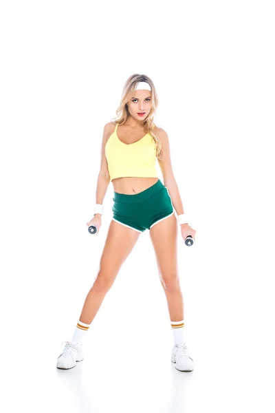 Attractive blonde fitness trainer in green shorts and yellow singlet with dumbbells on white background — Stock Photo