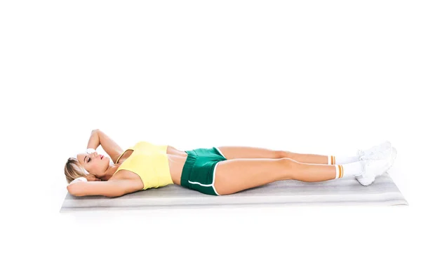 Entraîneur de fitness blonde en tenue de sport s'exerçant sur tapis de yoga isolé sur blanc — Photo de stock