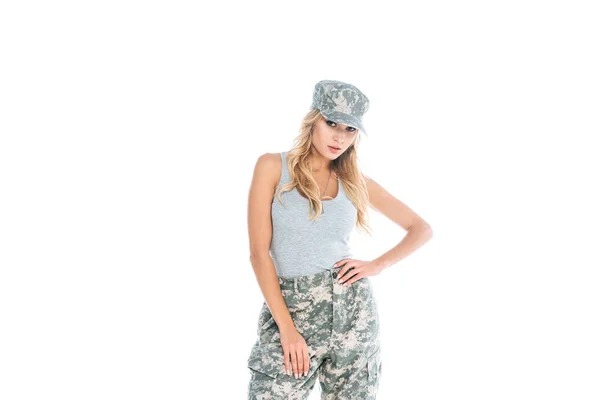 Atraente militarywoman em cinza t-shirt, calças de camuflagem e boné isolado em branco — Fotografia de Stock