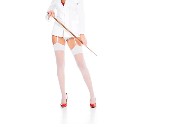 Обрезанный вид медсестры в коротком пальто, чулки и красные туфли держа указатель на белом фоне — стоковое фото