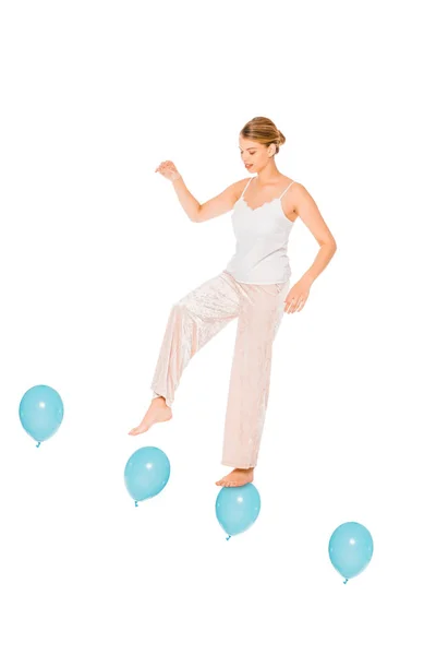 Girl in pyjamas levitating in air and standing on ballons isolated on white — Stock Photo