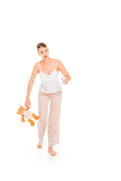Fille en pyjama tenant ours en peluche et verre isolé sur blanc — Photo de stock