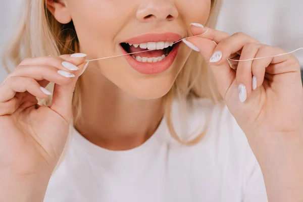 Cropped view of woman flossing teeth with dental floss — Stock Photo