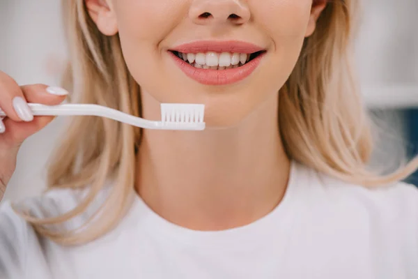 Vista parcial de la mujer sonriente sosteniendo el cepillo de dientes - foto de stock