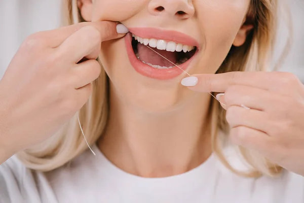 Cropped view of woman flossing teeth with dental floss — Stock Photo