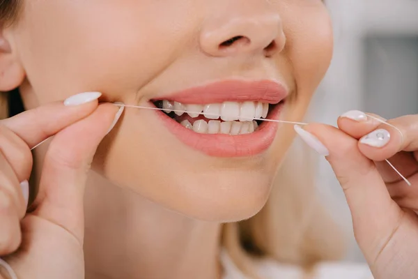 Partial view of woman flossing teeth with dental floss — Stock Photo