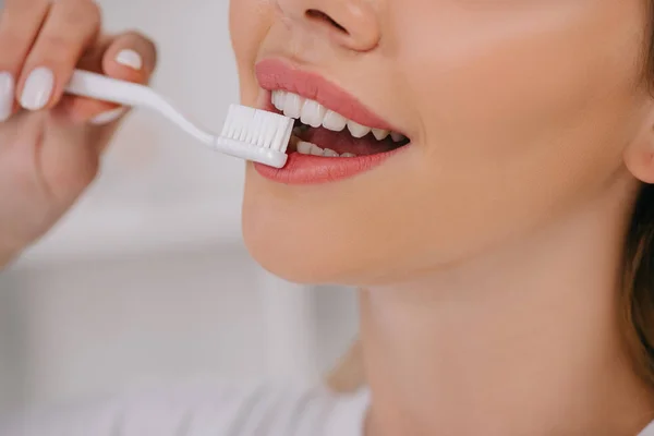 Recortado vista de la mujer sonriente cepillarse los dientes - foto de stock