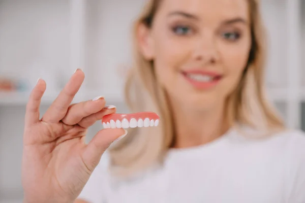 Enfoque selectivo de la cubierta de dientes con la mujer sonriente en el fondo - foto de stock