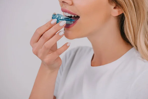 Vue recadrée de la femme portant un appareil dentaire d'entraînement orthodontique isolé sur blanc — Photo de stock