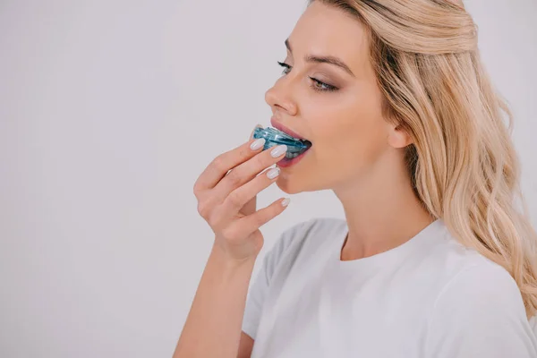 Красивая женщина надевает ортодонтические тренерские зубные скобки изолированные на белом с копировальным пространством — стоковое фото
