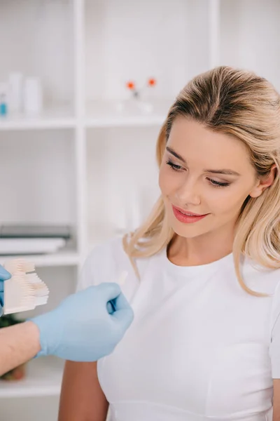 Schöne Frau beim Anblick der Zahnfarbenpalette während der Konsultation mit dem Zahnarzt in der Klinik — Stockfoto