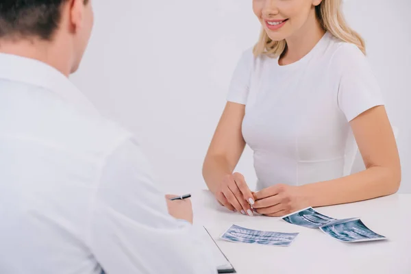 Teilansicht einer lächelnden Frau während der Konsultation mit Kieferorthopäden isoliert auf weiß — Stockfoto