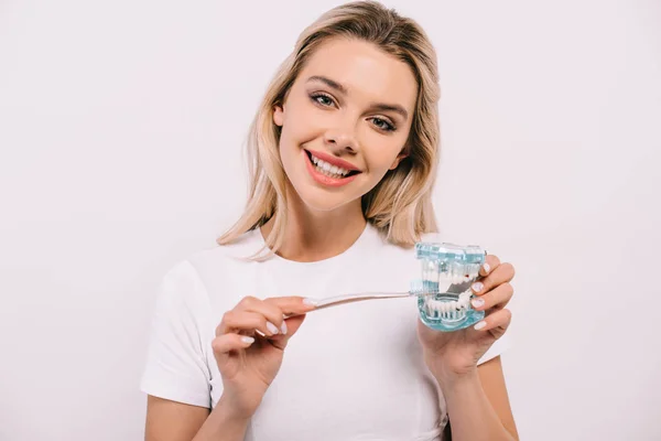 Bella donna sorridente spazzolatura modello mascella con spazzolino da denti e guardando la fotocamera isolata su bianco — Foto stock