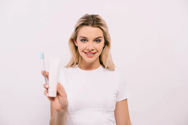 Hermosa mujer sosteniendo cepillo de dientes y pasta de dientes con espacio de copia aislado en blanco — Stock Photo