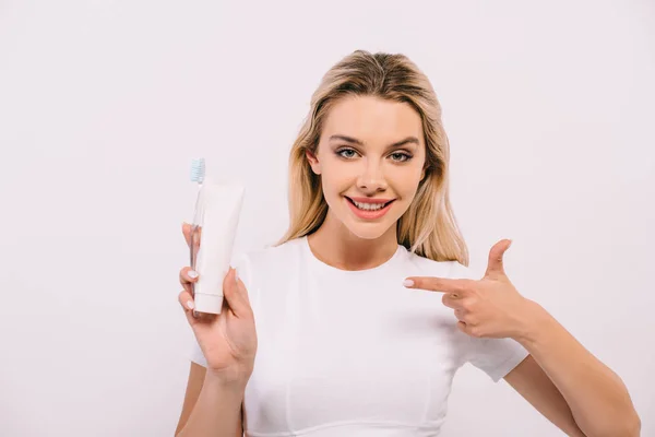 Schöne Frau zeigt mit dem Finger auf Zahnbürste und Zahnpasta mit Kopierraum isoliert auf weiß — Stockfoto