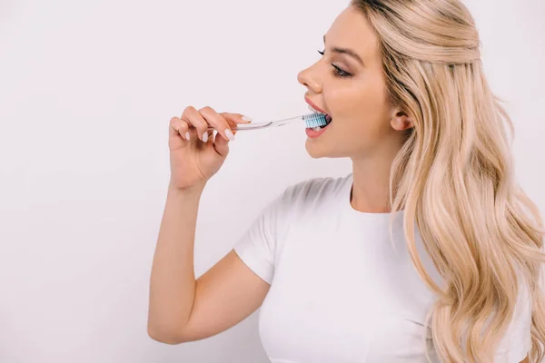 Beautiful woman in white t-shirt brushing teeth isolated on white with copy space — Stock Photo