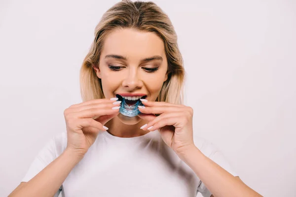 Beautiful woman putting on orthodontic trainer dental braces isolated on white — Stock Photo