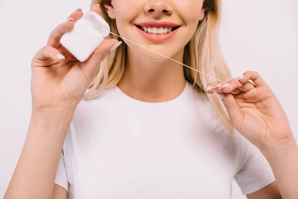 Vista recortada de la mujer sonriente sosteniendo hilo dental aislado en blanco - foto de stock