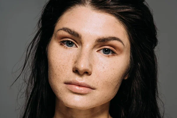 Attractive brunette young woman with freckles on face isolated on grey — Stock Photo