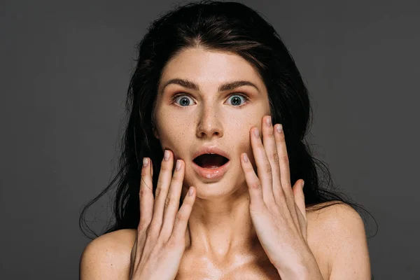 Schöne schockierte Frau mit Sommersprossen im Gesicht isoliert auf grau — Stockfoto