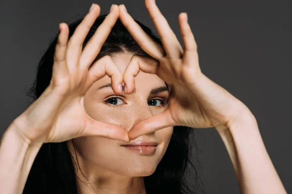 Beautiful tender woman showing heart sign isolated on grey — Stock Photo