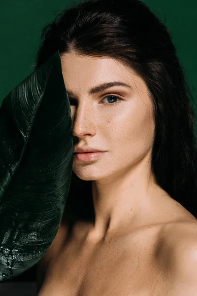 Menina bonita com pele perfeita posando com folha de palma isolada no verde — Fotografia de Stock