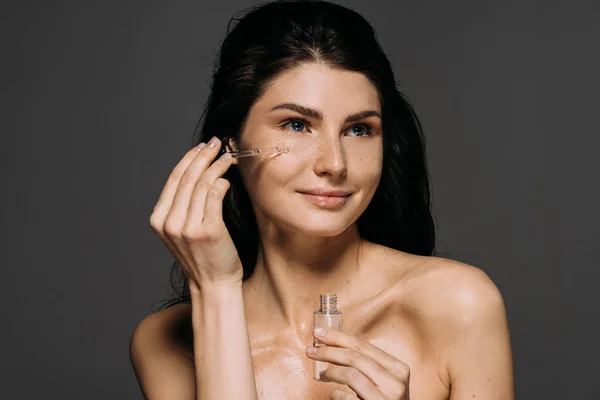 Séduisante femme nue appliquant sérum avec pipette isolé sur gris — Photo de stock