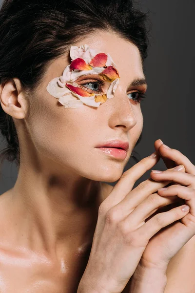 Tender brunette girl with petals around eye isolated on grey — Stock Photo