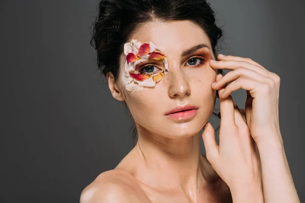 Tenera ragazza con petali floreali intorno all'occhio isolato su grigio — Foto stock