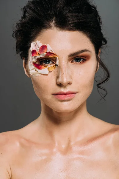 Beautiful brunette woman with floral petals around eye isolated on grey — Stock Photo