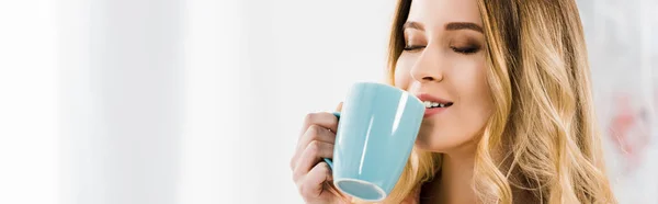 Cropped view of relaxed blonde woman drinking coffee with closed eyes — Stock Photo