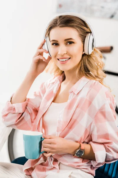 Felice giovane donna in cuffia ascoltare musica e bere caffè — Foto stock
