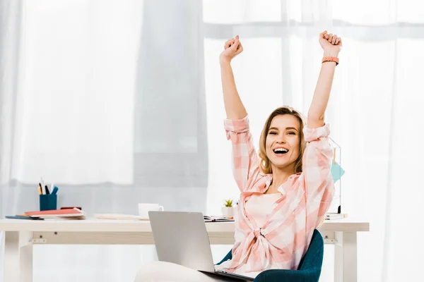 Happy young woman with laptop laughing and holding hands up — Stock Photo