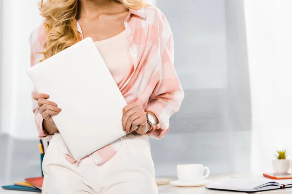 Partial view of blonde woman in checkered shirt holding laptop — Stock Photo