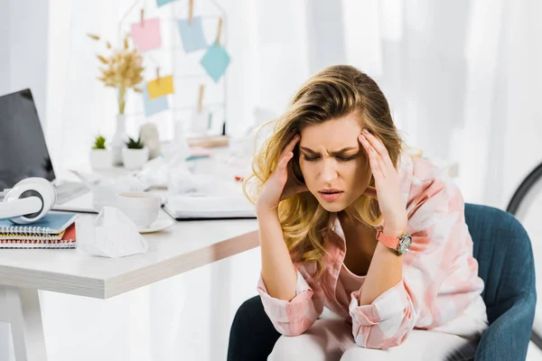 Müde blonde Frau im karierten Hemd fühlt sich am Arbeitsplatz schlecht und berührt den Kopf — Stockfoto