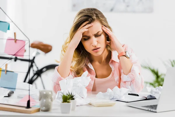 Blonde woman feeling bad and touching head with closed eyes at workplace — Stock Photo