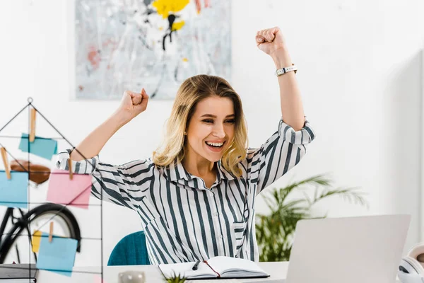 Happy girl in striped shirt looking at laptop and waving hands — Stock Photo