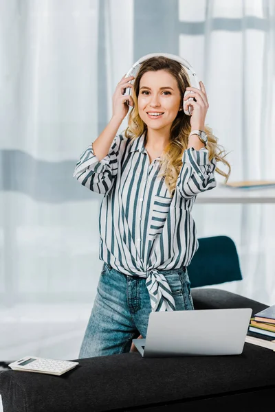 Belle femme bouclée en chemise rayée écoutant de la musique dans les écouteurs — Photo de stock