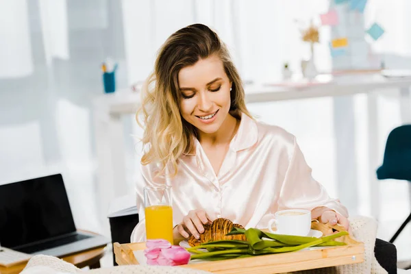 Junge Frau im Satin-Pyjama beim Frühstück mit einem Lächeln — Stockfoto