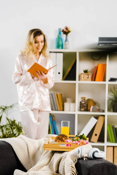 Jeune femme blonde en pyjama livre de lecture le matin — Photo de stock