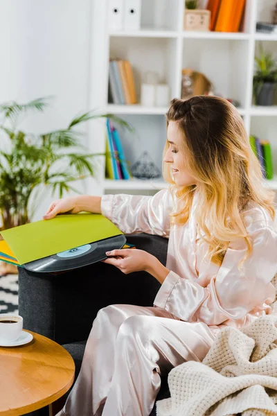 Jovem mulher em pijama de cetim segurando recorde de vinil em casa — Fotografia de Stock