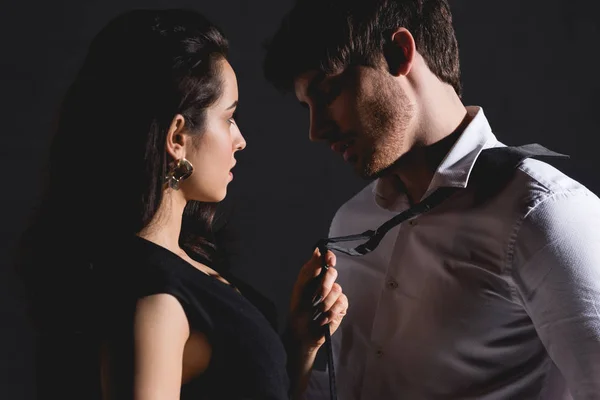 Man in white shirt and woman in dress standing and looking to each other isolated on black — Stock Photo